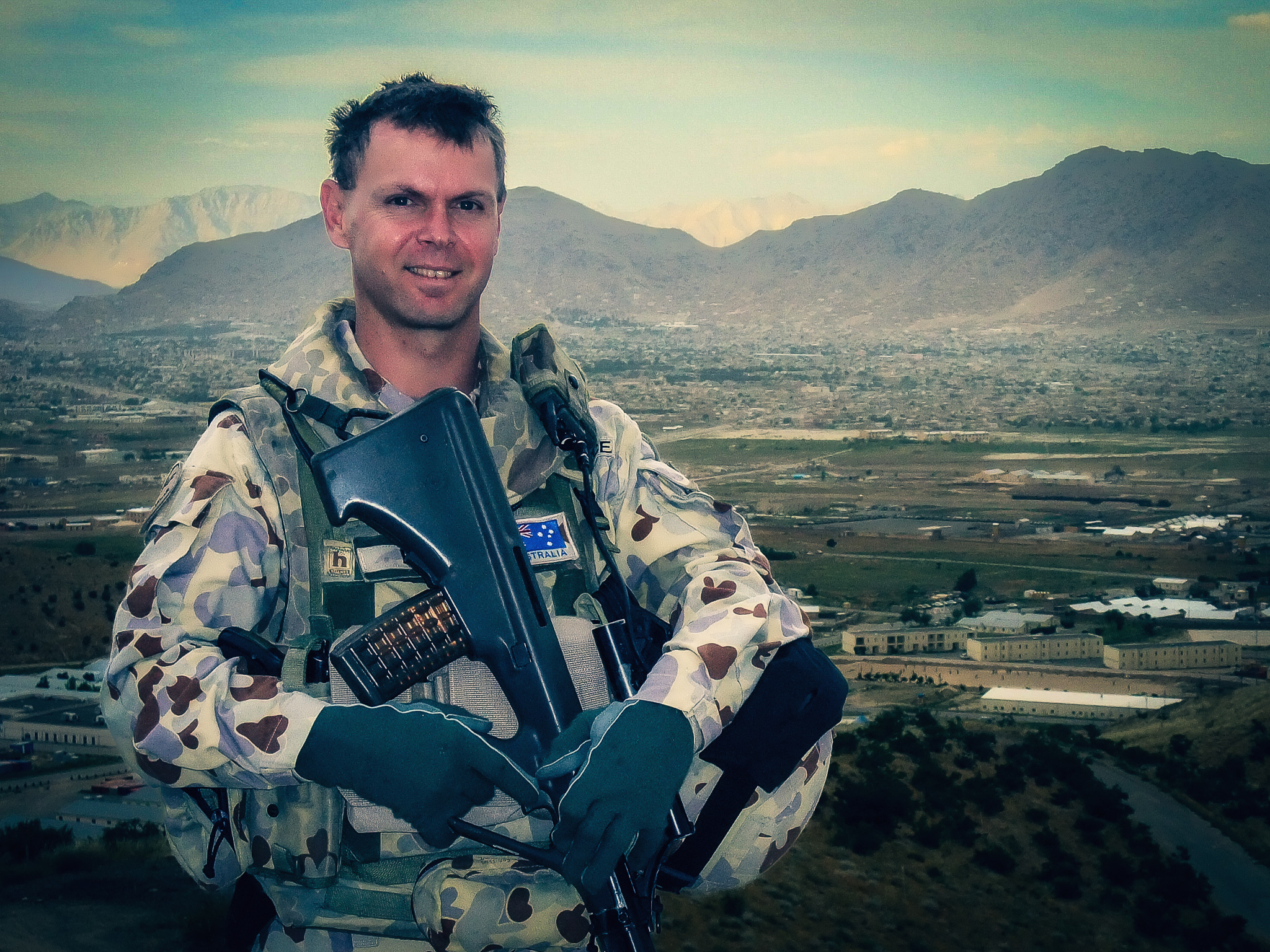 Lyle Holt in Australian DPCU combat uniform in Afghanistan, Kabul valley and surrounding mountains in the background