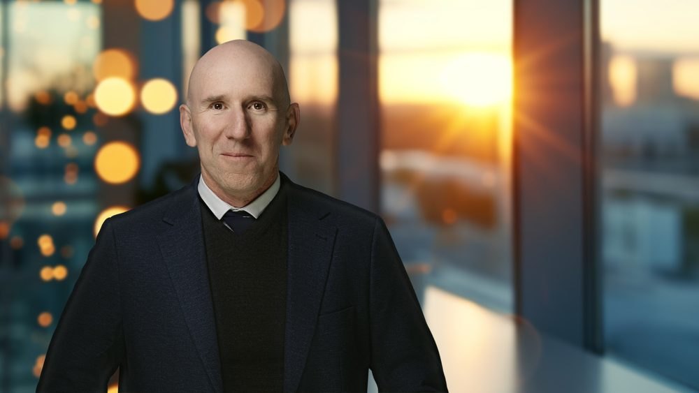 Dr Anthony Walker in an office setting with a city skyline at dusk