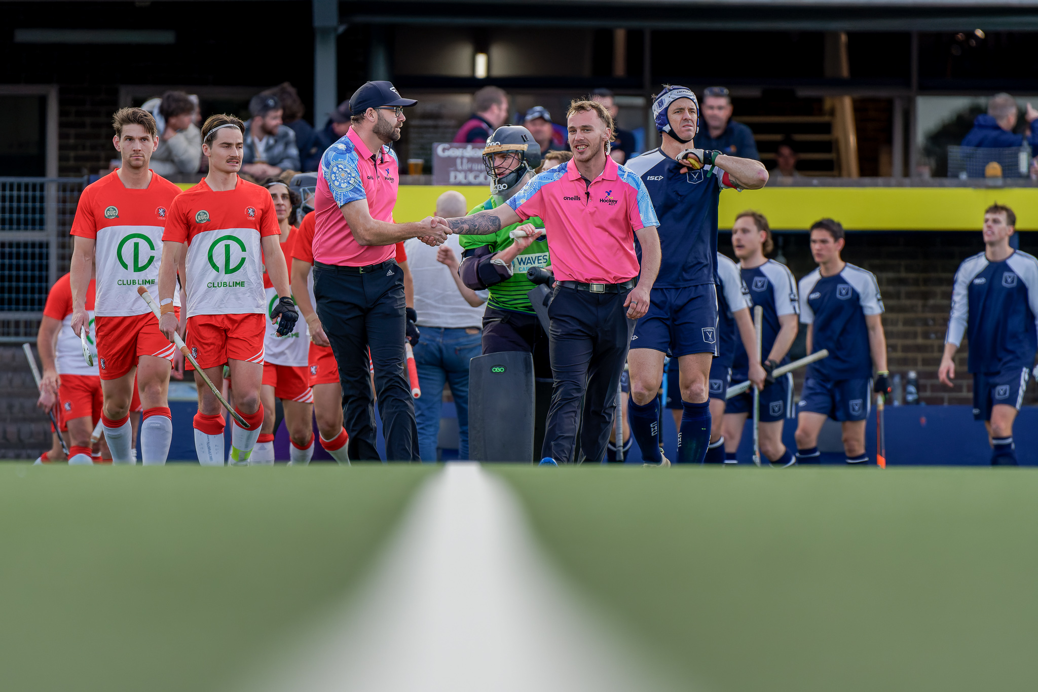 Hockey ACT men's teams pre-match handshake — Club Lime and opposing squad, umpires in pink, competition sportsmanship
