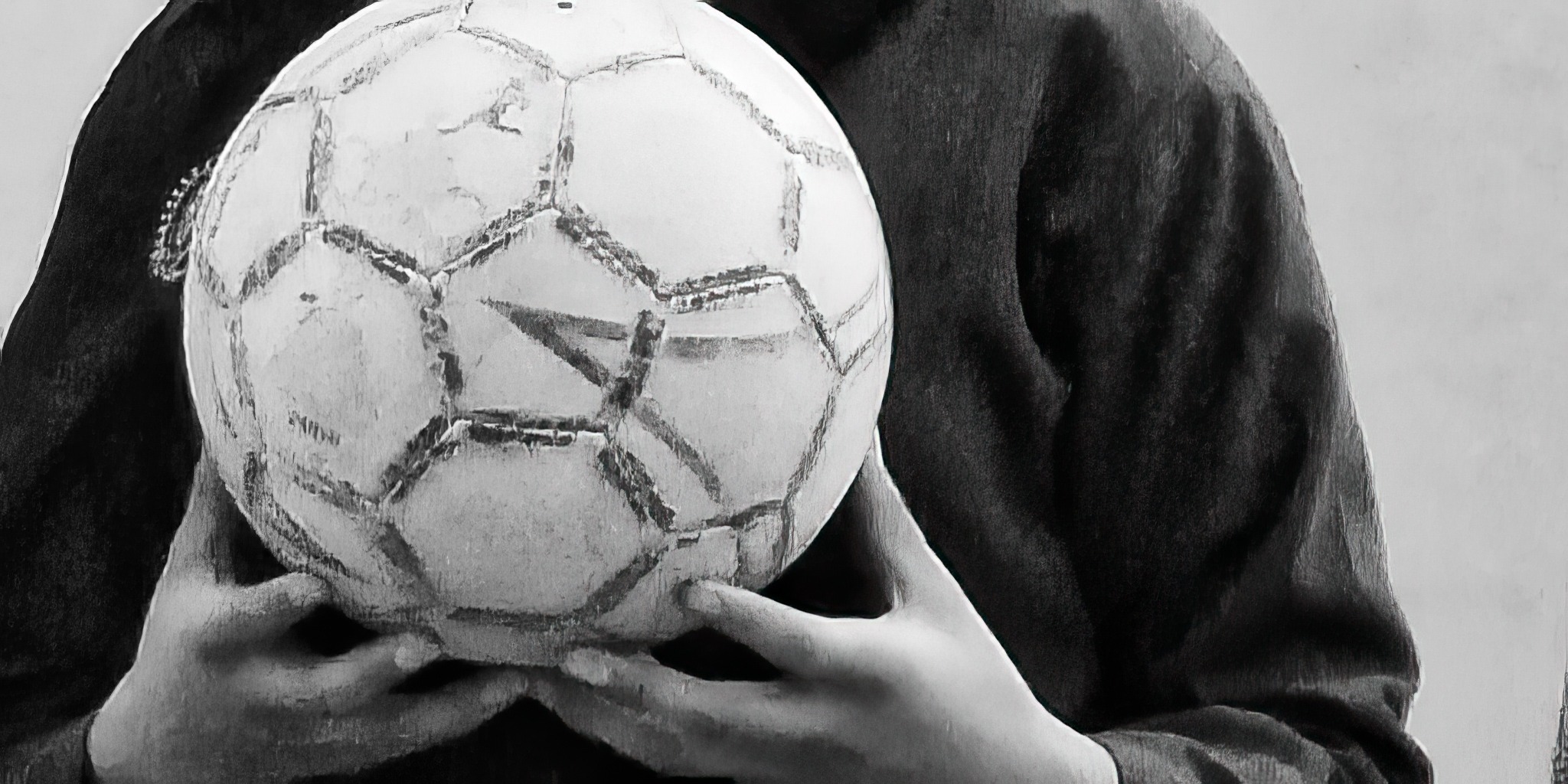 Hands holding a worn football against a wall, outskirts of Kabul