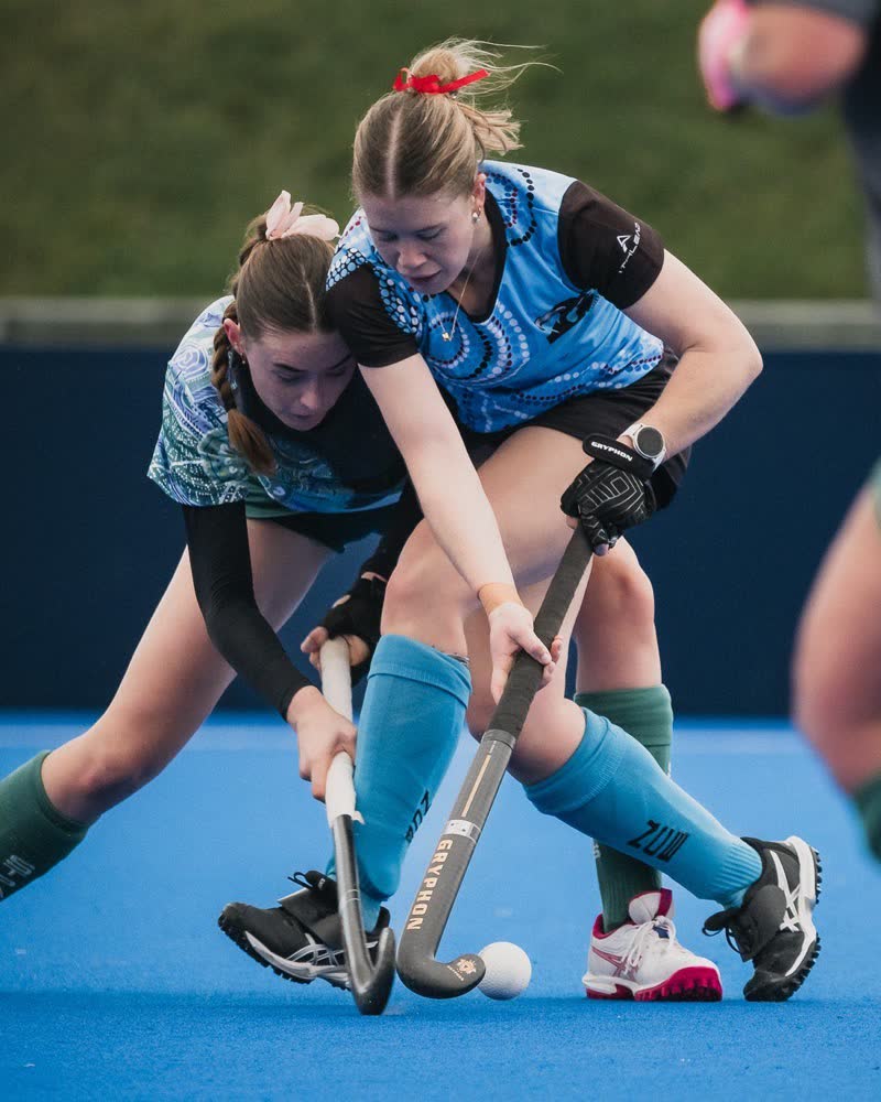 Two players contest the ball during a Hockey ACT Reconciliation Round match