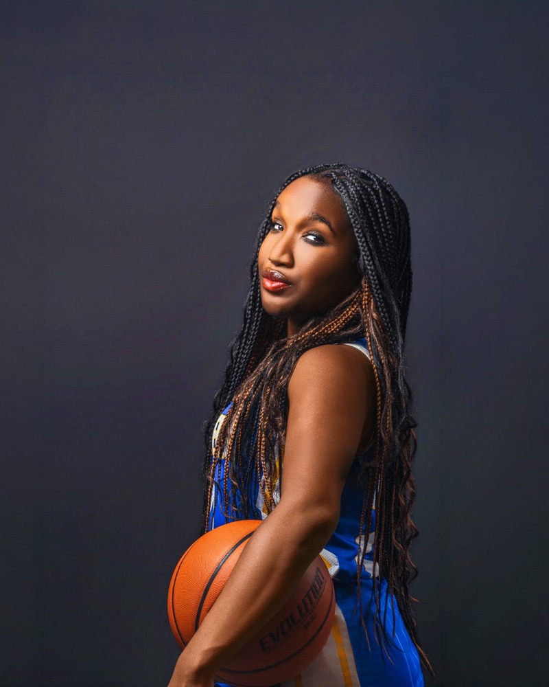 The same basketball player side-on with the ball, looking back over her shoulder
