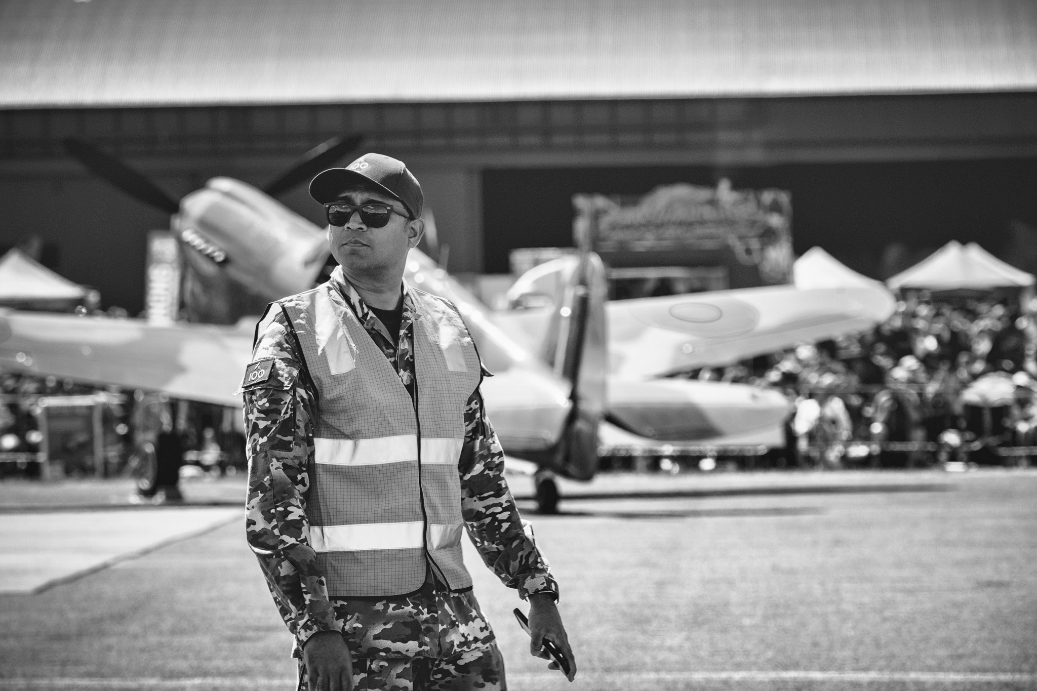 RAAF member in hi-vis vest, warbirds and crowd in background