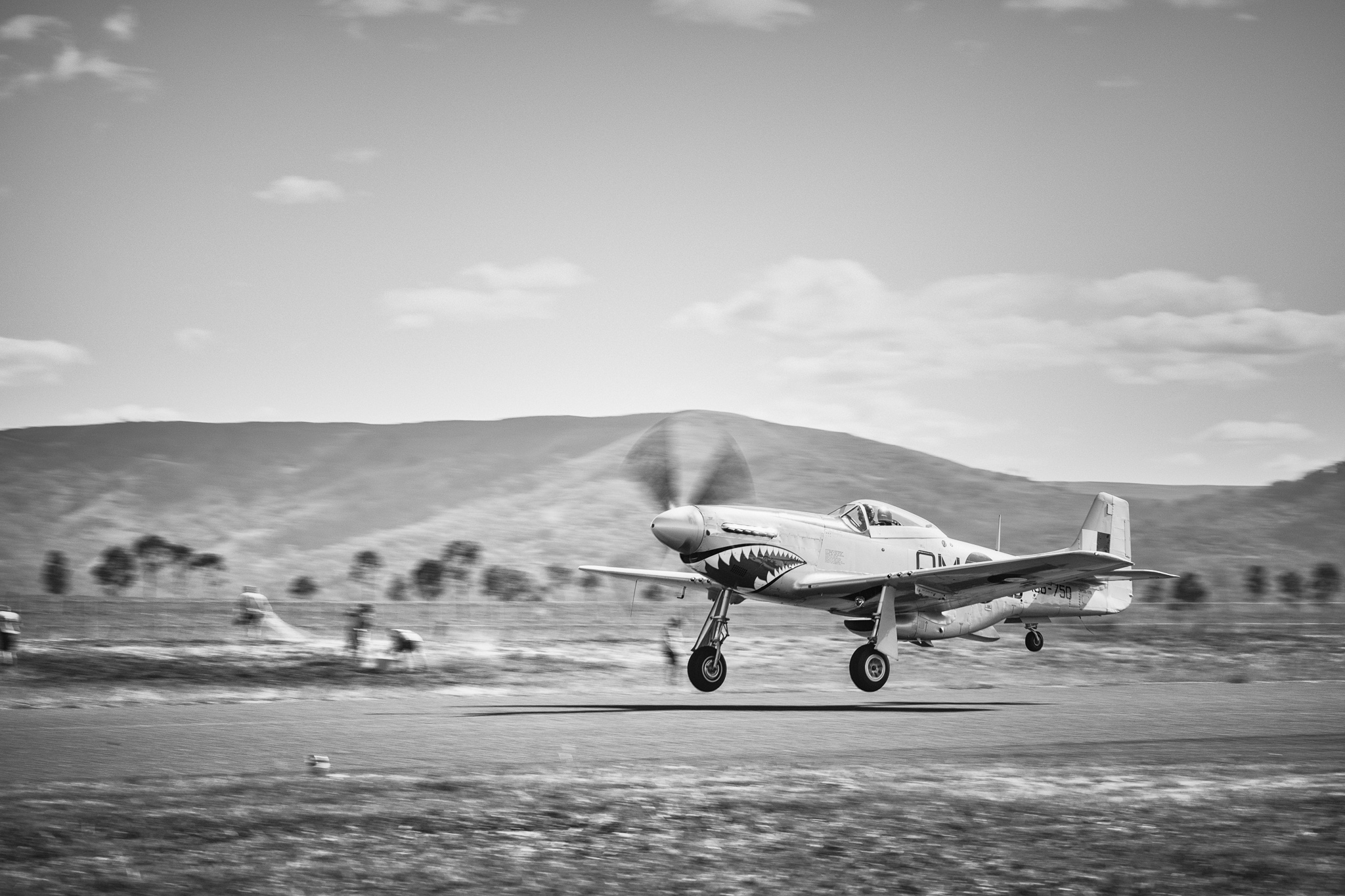 Mustang lifting off runway, mountains background, panning motion blur