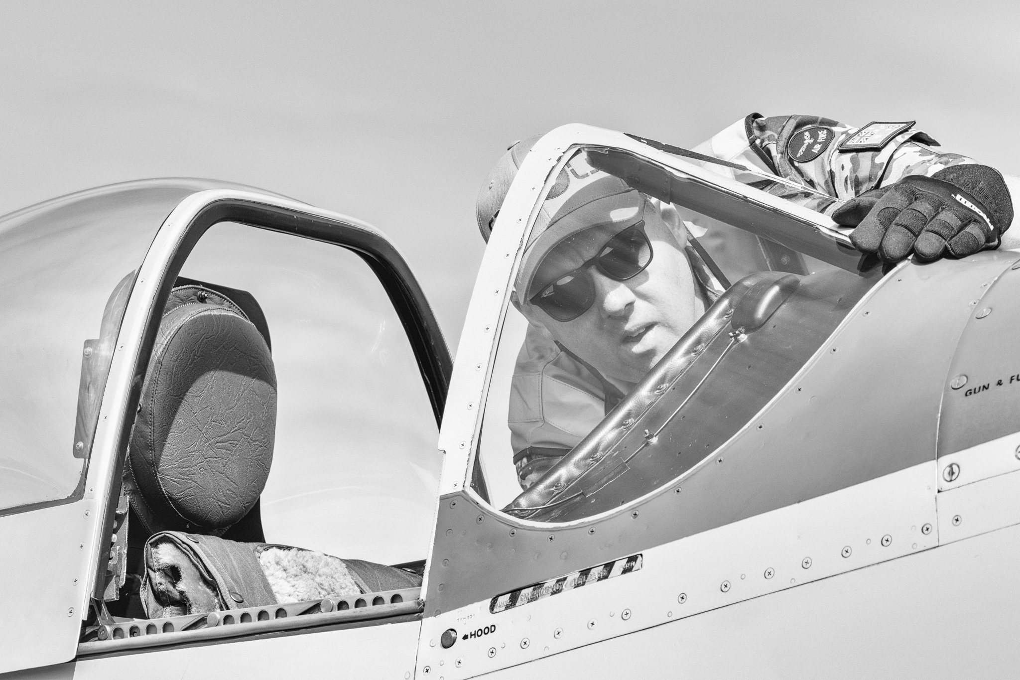 Pilot in open cockpit checking controls, sunglasses, pre-flight routine