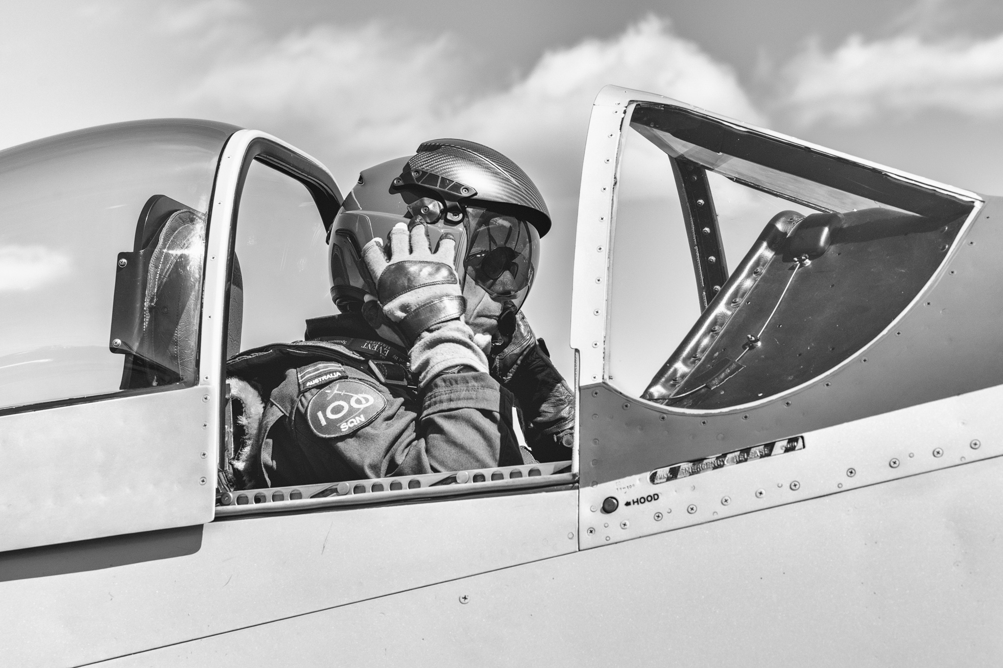 Helmeted pilot in cockpit, 100SQN patch visible, mission-ready