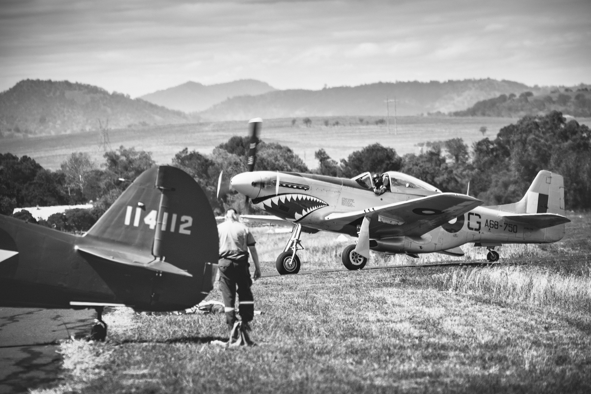 Ground handler walking near parked Mustang, landscape wide, operational scale
